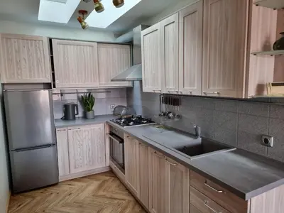 a kitchen with wooden cabinets and stainless steel appliances at Old Town Jiva apartment in Kaunas