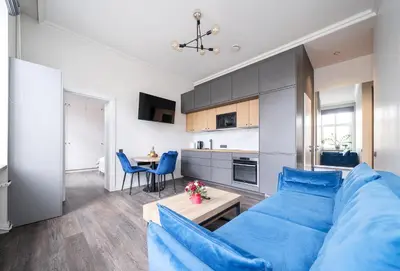 a living room with a blue couch and a kitchen at Jasinskio Apartament - Lollo Stay in Vilnius