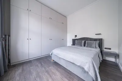 a white bedroom with a bed and white cabinets at Jasinskio Apartament - Lollo Stay in Vilnius