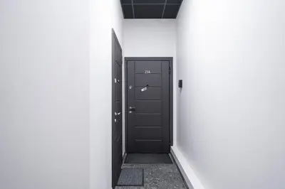 a hallway with a black door and a white wall at Jasinskio Apartament - Lollo Stay in Vilnius