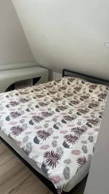 a bedroom with a bed with a flower pattern on it at Centro apartamentai in Kalvarija