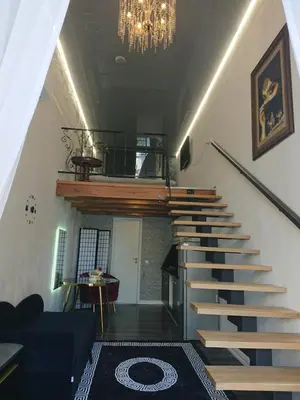 a staircase in a living room with a chandelier at Loftas in Druskininkai