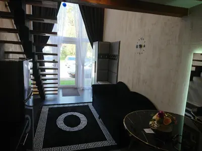 a living room with a table and a spiral staircase at Loftas in Druskininkai