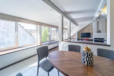 a dining room with a table and chairs and windows at Grand Apt with air conditioning in Kaunas