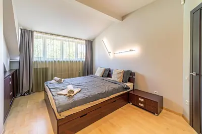 a bedroom with a bed with a wooden floor and a window at Grand Apt with air conditioning in Kaunas