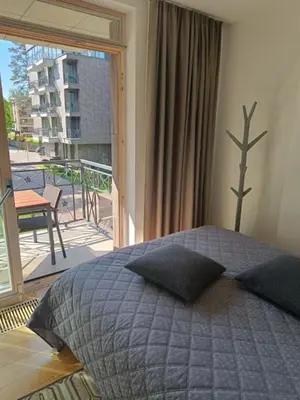 a bedroom with a bed in front of a balcony at Moderniškas ir jaukus butas gamtos apsuptyje in Druskininkai