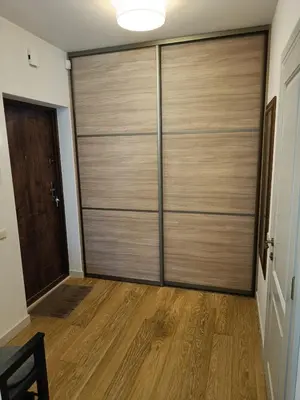 a sliding door in a room with a wooden floor at Moderniškas ir jaukus butas gamtos apsuptyje in Druskininkai