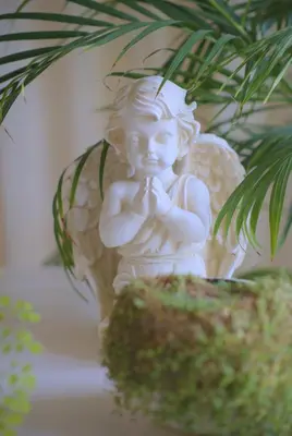 a statue of an angel praying next to a plant at Cozy house in Vilnius in Vilnius