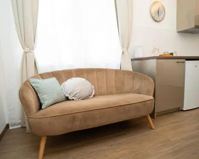 a brown couch with two pillows on it in front of a window at Downhill Apartment with a Private Terrace in Kaunas