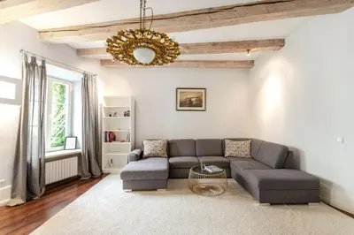 a living room with a couch and a chandelier at 3 Bedroom Duplex Apartment next to the Gates of Dawn in Vilnius