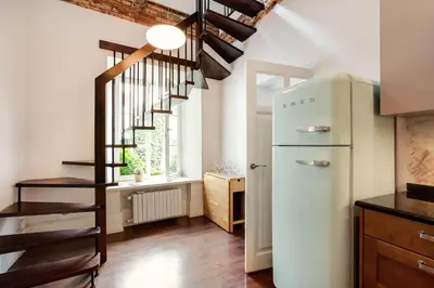 a kitchen with a refrigerator and a staircase at 3 Bedroom Duplex Apartment next to the Gates of Dawn in Vilnius