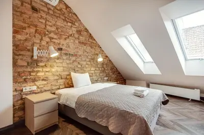 a bedroom with a bed and a brick wall at 3 Bedroom Duplex Apartment next to the Gates of Dawn in Vilnius