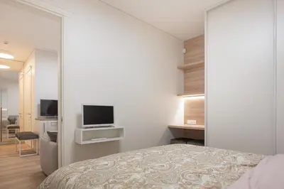 a bedroom with a bed and a tv on a wall at Cathedral apartment, perfect for couples in Vilnius