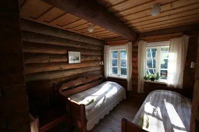a bedroom with a bed in a room with wooden walls at Miškiniškės in Ignalina