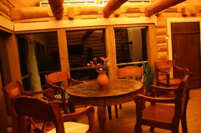 a wooden room with a table and chairs and a vase with flowers at Miškiniškės in Ignalina