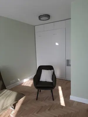 a black chair with a white pillow in a room at Visinskio apartamentai in Šiauliai