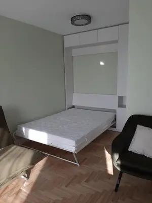 a small room with a bed and a chair at Visinskio apartamentai in Šiauliai