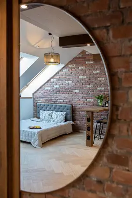 a mirror reflecting a bedroom with a bed in a brick wall at M8 Exclusive Studio Apartment in Kaunas