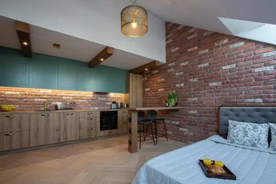 a kitchen with a brick wall and a bed in a room at M8 Exclusive Studio Apartment in Kaunas