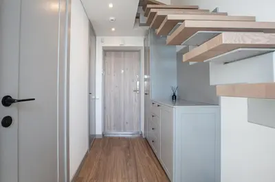 a kitchen with white cabinets and a wooden floor at M8 Modern Two-Floor Apartment in Kaunas
