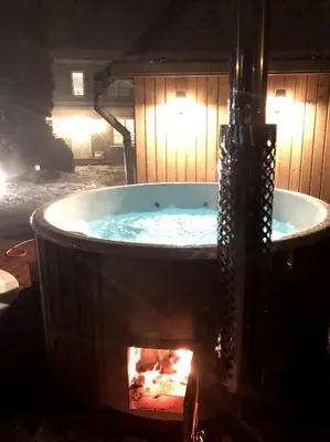 a hot tub with a fireplace in a room at Amazing Riverside home/Kayaks&Sauna/Grill&Garden in Pabradė