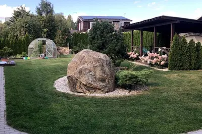 a large rock sitting in the grass in a yard at Amazing Riverside home/Kayaks&Sauna/Grill&Garden in Pabradė