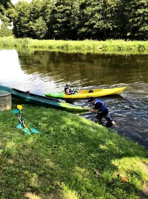 two people in kayaks on a river next to at Amazing Riverside home/Kayaks&Sauna/Grill&Garden in Pabradė