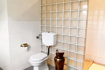 a bathroom with a toilet and a tile wall at Amazing Riverside home/Kayaks&Sauna/Grill&Garden in Pabradė