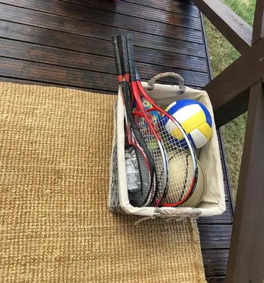 a basket of tennis rackets and a ball on a bench at Amazing Riverside home/Kayaks&Sauna/Grill&Garden in Pabradė