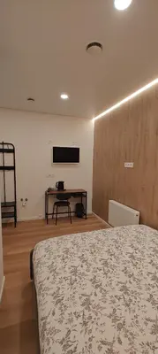a bedroom with a bed and a desk with a television at 14 New Airport Apartment in Vilnius