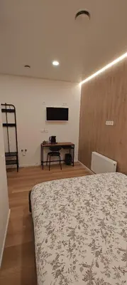 a bedroom with a bed and a table and a tv at 14 New Airport Apartment in Vilnius