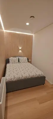 a bedroom with a large bed with a wooden headboard at 14 New Airport Apartment in Vilnius