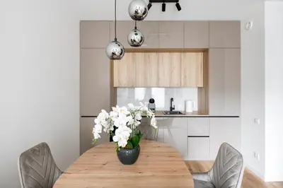 a dining room table with a vase of flowers on it at Žalia kopa Metropolis Vilnius in Vilnius