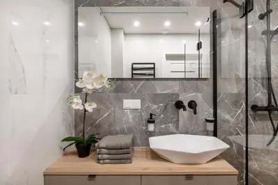 a bathroom with a white sink and a shower at Žalia kopa Metropolis Vilnius in Vilnius