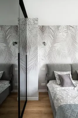 a bedroom with two beds and a wall with palm leaves at Žalia kopa Metropolis Vilnius in Vilnius