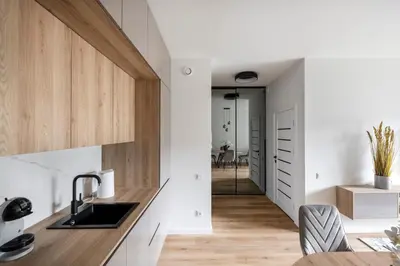 a kitchen with white walls and wooden cabinets at Žalia kopa Metropolis Vilnius in Vilnius
