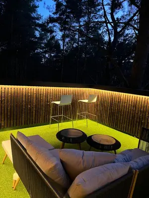 a patio with a couch and two tables and chairs at Treehouse Virš Bedugnės in Jurbarkas