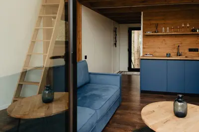 a living room with a blue couch and a wooden table at Treehouse Virš Bedugnės in Jurbarkas