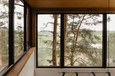 a room with windows looking out onto a field at Treehouse Virš Bedugnės in Jurbarkas