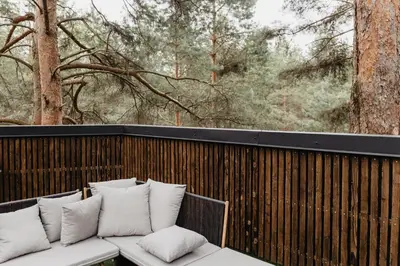 a white couch sitting on a wooden fence with pillows at Treehouse Virš Bedugnės in Jurbarkas