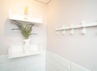 a bathroom with white shelves and a vase on the wall at Downhill Apartment on the Groundfloor in Kaunas
