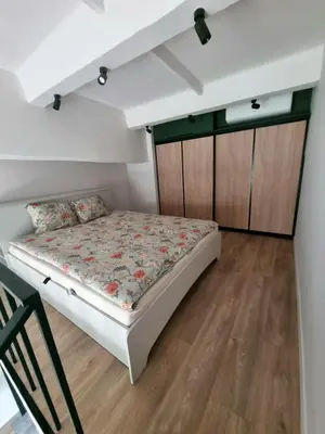 a small bedroom with a bed and wooden cabinets at Cozy Loft in Kaunas