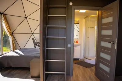 a bedroom with a bed and a door leading to a bathroom at Greenery Kupolai in Kalveliai
