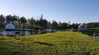 a grassy field next to a river with domes at Greenery Kupolai in Kalveliai