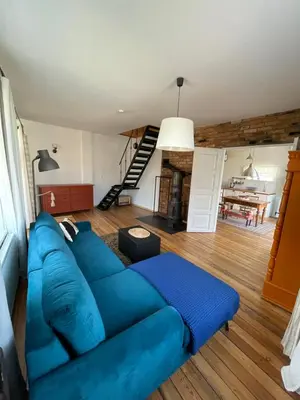 a blue couch in a living room with a staircase at Namas senamiestyje in Kėdainiai