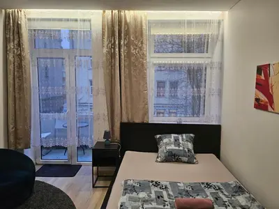 a bedroom with a bed and two windows at Kauno apartamentai su balkonu in Kaunas