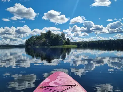 a pink kayak on a lake with clouds in the sky at Glamping Zarasai in Palivarkas