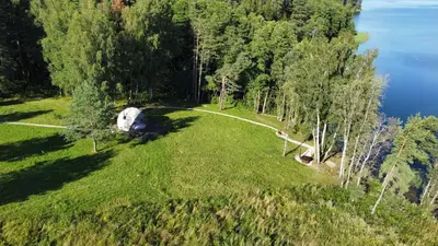 an aerial view of a grassy field next to a lake at Glamping Zarasai in Palivarkas