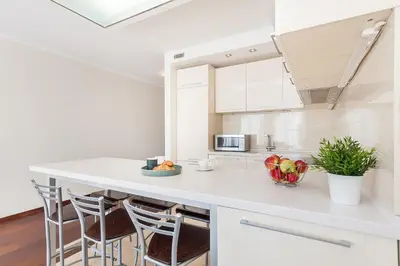 a kitchen with a white counter and stools at Central Apartment in Gedimino Av by URBAN RENT in Vilnius