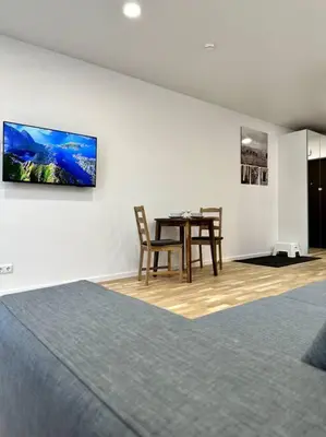 a dining room with a table and a tv on a wall at Wolfie Apartment, City Center in Vilnius